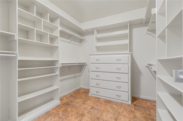 spacious closet featuring stone finish flooring
