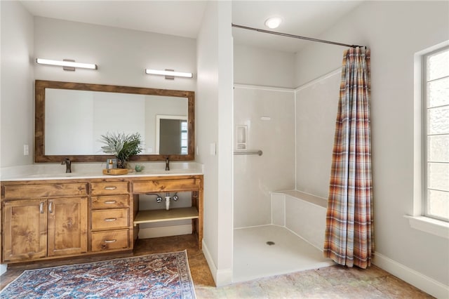 bathroom featuring double vanity, baseboards, a sink, and a shower