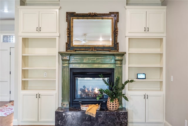 living room featuring crown molding, a multi sided fireplace, and built in shelves