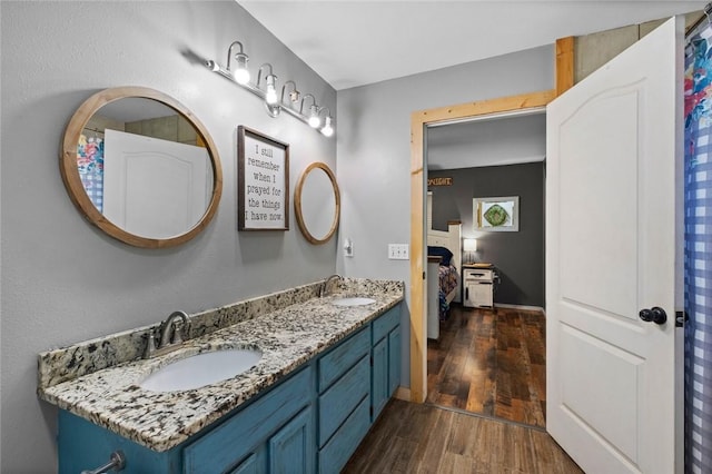 ensuite bathroom featuring a sink, ensuite bathroom, double vanity, and wood finished floors