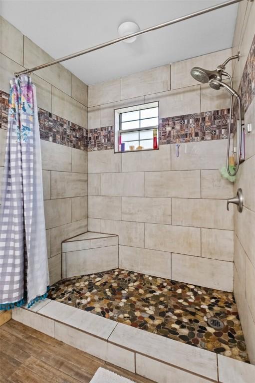 full bathroom featuring tiled shower and wood finished floors