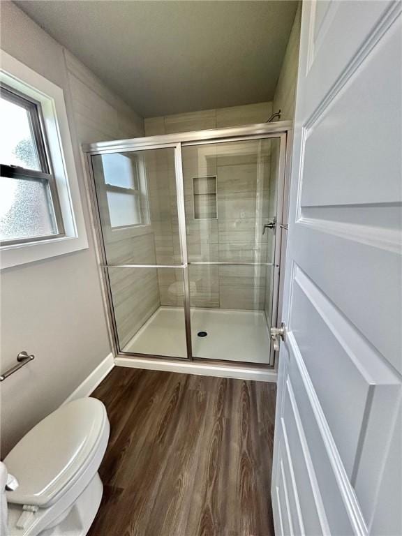 bathroom with toilet, a shower stall, and wood finished floors