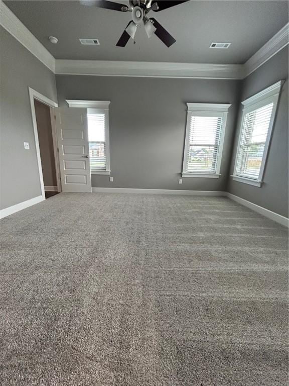 empty room with plenty of natural light, ornamental molding, ceiling fan, and visible vents