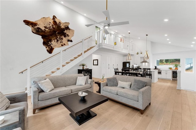 living area with stairway, high vaulted ceiling, recessed lighting, and light wood-style flooring