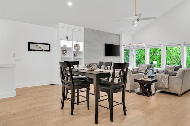 dining room featuring a towering ceiling, a wealth of natural light, and light wood-style floors