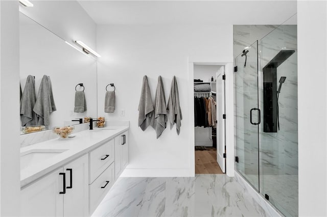 bathroom with double vanity, a walk in closet, a marble finish shower, and marble finish floor