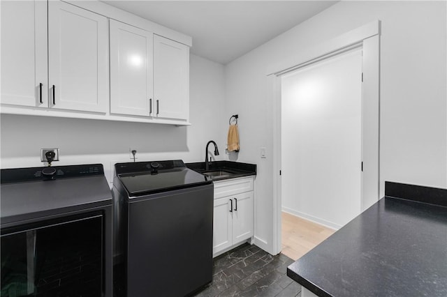 washroom with baseboards, a sink, cabinet space, and washing machine and dryer