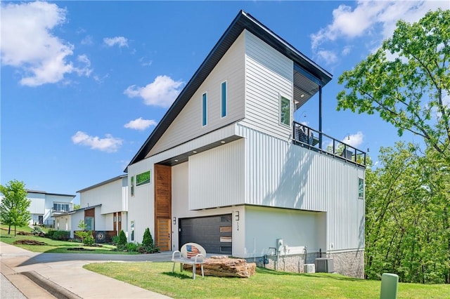 exterior space featuring an attached garage, a lawn, and central air condition unit
