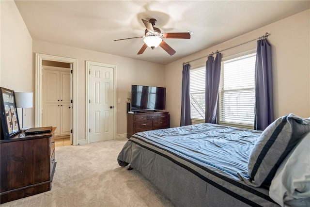 bedroom with ceiling fan, light carpet, and baseboards