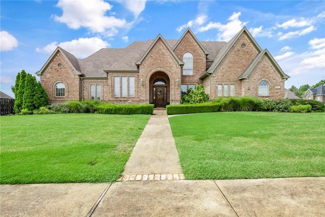 view of front of house featuring brick siding, a shingled roof, and a front yard