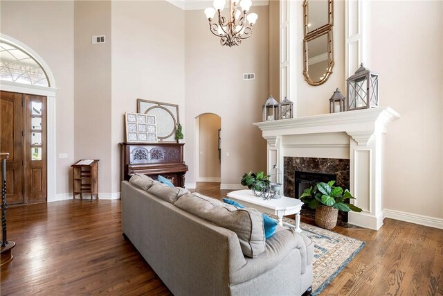 living area featuring arched walkways, a high ceiling, wood finished floors, and a premium fireplace