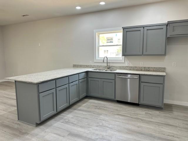 kitchen with a sink, gray cabinets, a peninsula, and dishwasher