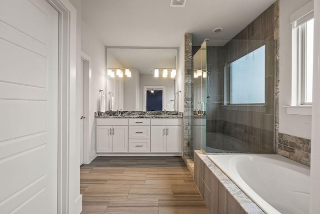 full bath with visible vents, double vanity, a bath, a shower stall, and a sink