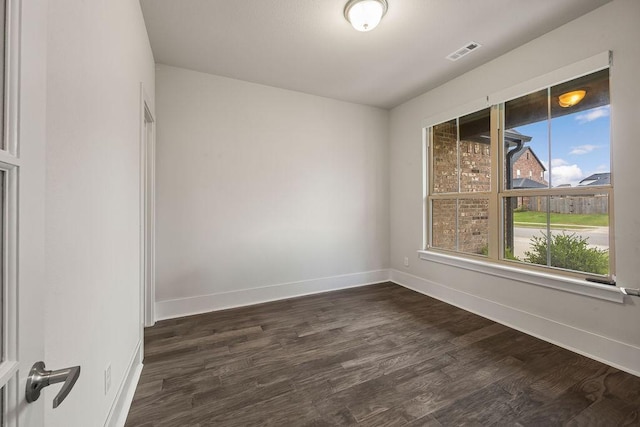 spare room featuring baseboards, visible vents, and dark wood finished floors