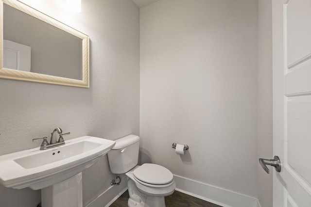 bathroom featuring toilet, baseboards, and wood finished floors