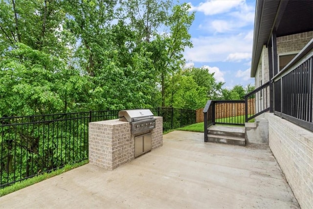 view of patio featuring grilling area, fence, and exterior kitchen