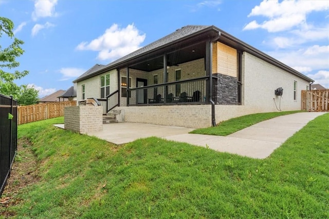 rear view of property featuring a lawn, a fenced backyard, a patio area, and brick siding