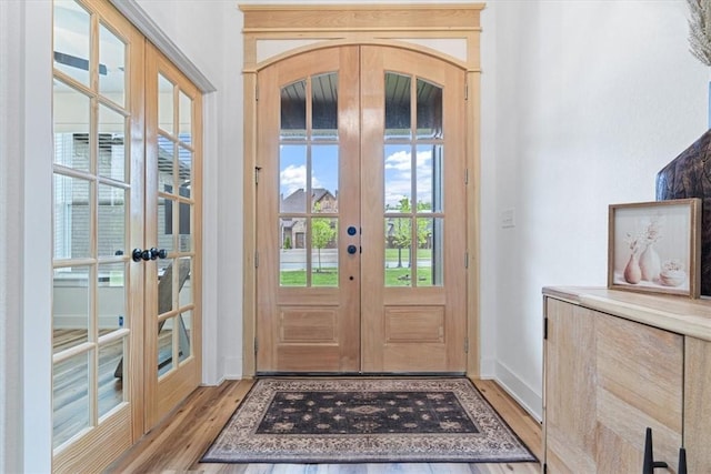 doorway featuring french doors, light wood-style floors, and baseboards
