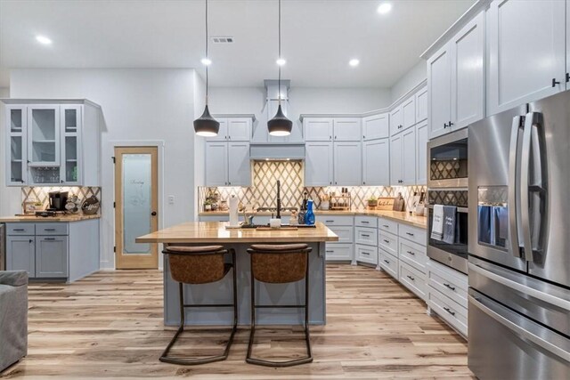 kitchen featuring a center island, decorative backsplash, light wood finished floors, and appliances with stainless steel finishes