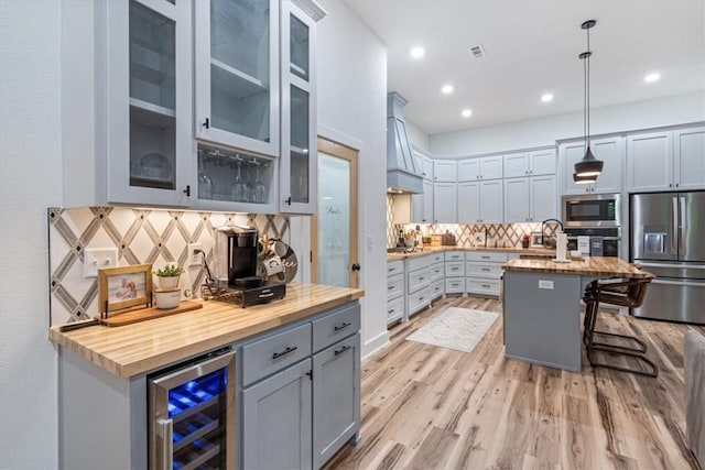 kitchen featuring wood counters, decorative backsplash, stainless steel appliances, and beverage cooler