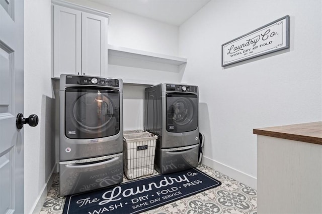 clothes washing area with baseboards, cabinet space, and washer and clothes dryer