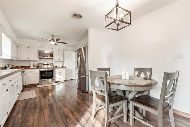 dining area with visible vents, dark wood finished floors, and ceiling fan with notable chandelier