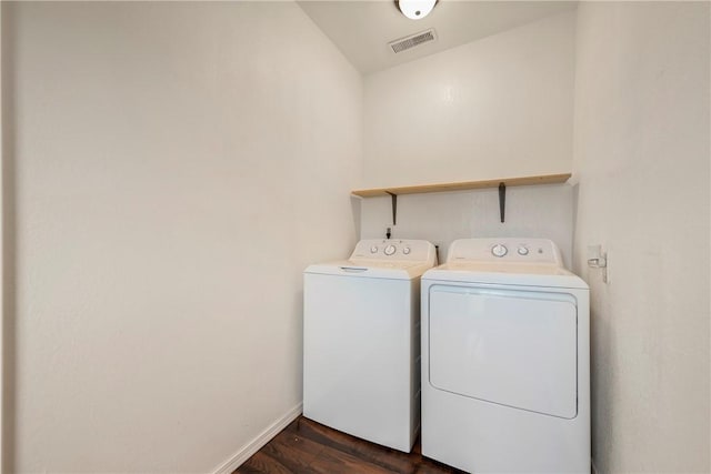 laundry area with laundry area, dark wood finished floors, baseboards, visible vents, and washing machine and dryer
