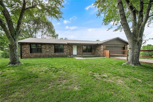 single story home featuring an attached garage, brick siding, fence, and a front yard