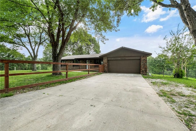 ranch-style home with concrete driveway, fence, and a garage