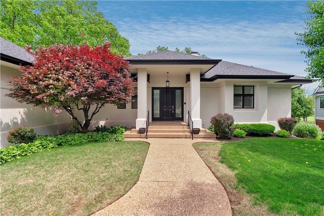 view of front of home featuring a shingled roof, a front lawn, and stucco siding