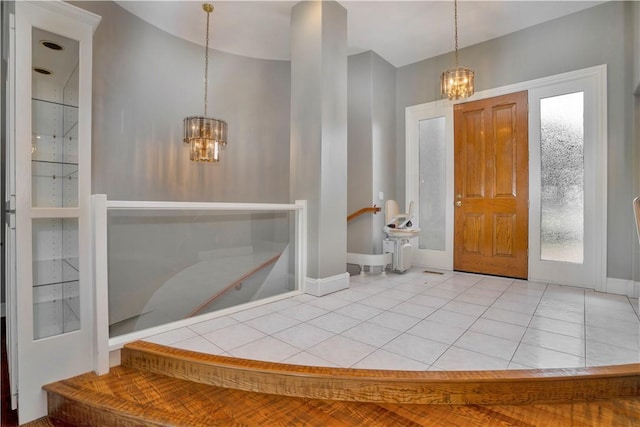 foyer entrance with tile patterned flooring, baseboards, and a chandelier