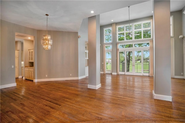 unfurnished living room featuring baseboards, dark wood finished floors, and a notable chandelier