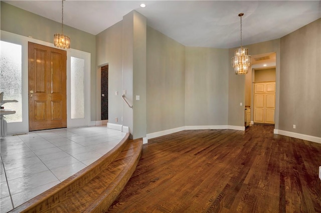 foyer with baseboards, a notable chandelier, and wood finished floors