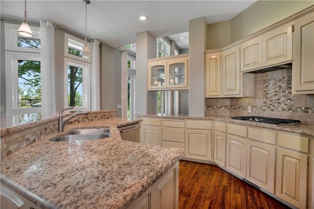 kitchen with a sink, backsplash, stainless steel appliances, and cream cabinetry