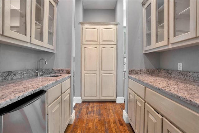 kitchen with dark wood-style flooring, glass insert cabinets, light stone counters, a sink, and dishwasher