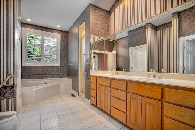 bathroom with wallpapered walls, a sink, tile patterned flooring, and a garden tub