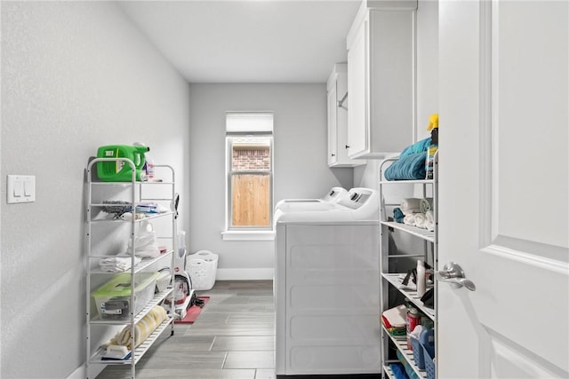 washroom with cabinet space, baseboards, washer and clothes dryer, and light wood-style floors
