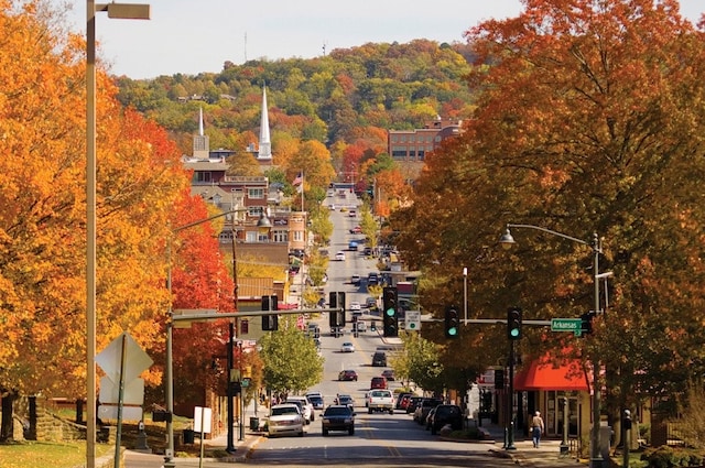 view of road featuring curbs, traffic signs, traffic lights, street lights, and sidewalks