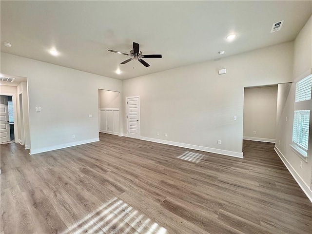 interior space with baseboards, a ceiling fan, wood finished floors, and visible vents