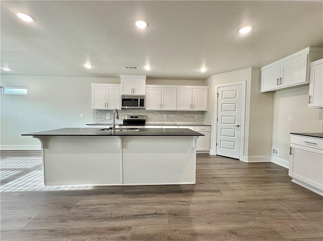 kitchen with dark wood-style floors, white cabinetry, a sink, backsplash, and stainless steel appliances