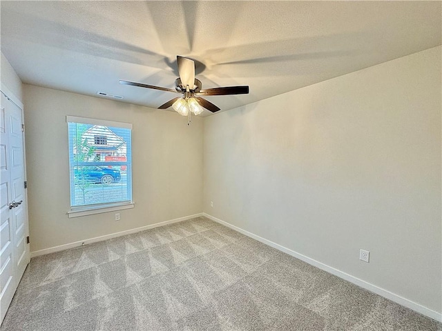 empty room featuring baseboards, ceiling fan, visible vents, and light colored carpet
