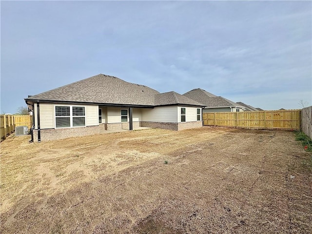 back of house featuring brick siding, cooling unit, and a fenced backyard