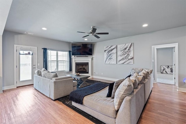 living area featuring a fireplace, a ceiling fan, recessed lighting, and wood finished floors