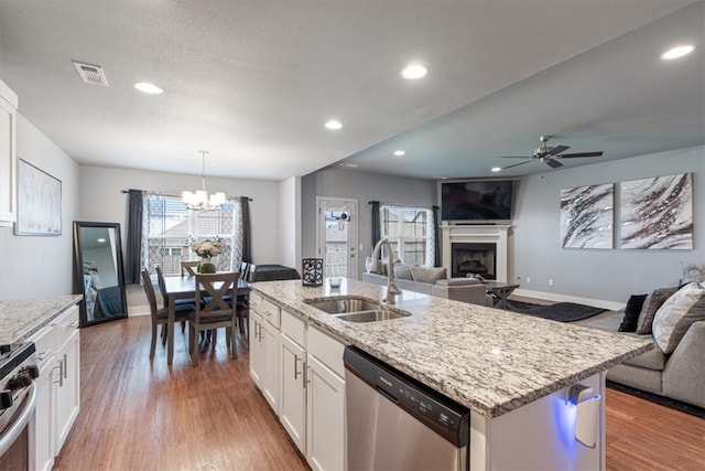 kitchen featuring a sink, light wood-style floors, a fireplace, stainless steel appliances, and open floor plan