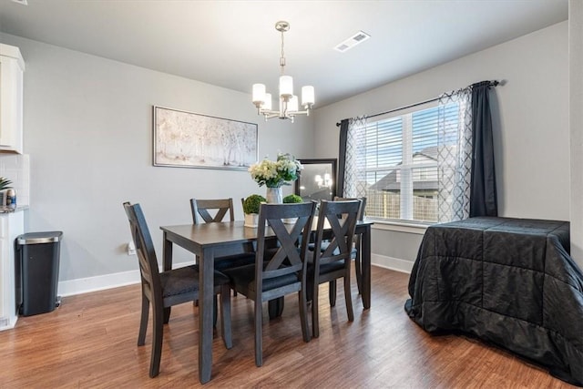 dining space featuring baseboards, light wood-style flooring, a notable chandelier, and visible vents