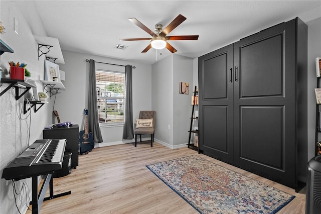 living area featuring baseboards, a ceiling fan, light wood-type flooring, and visible vents