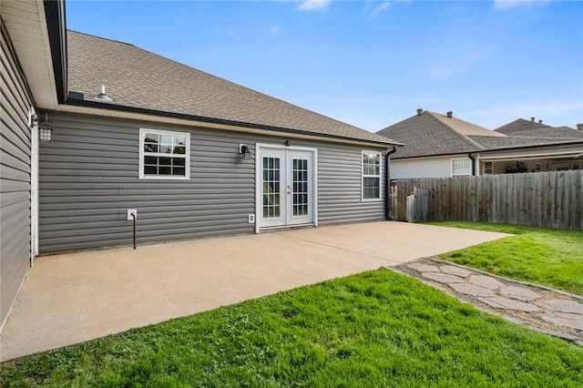 back of house with fence, roof with shingles, french doors, a patio area, and a lawn