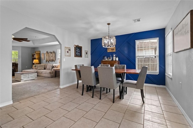 dining room featuring arched walkways, baseboards, visible vents, and ceiling fan with notable chandelier
