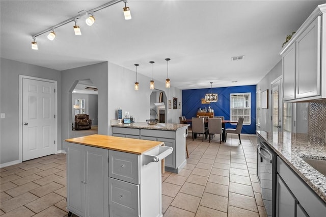 kitchen featuring a kitchen island, visible vents, arched walkways, stainless steel dishwasher, and butcher block counters
