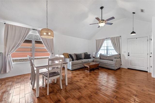 living area featuring a ceiling fan, high vaulted ceiling, visible vents, and wood finished floors